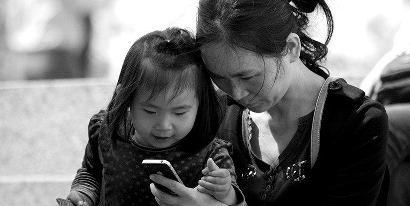 Chinese grandmother and her granddaughter playing with an iPhone
